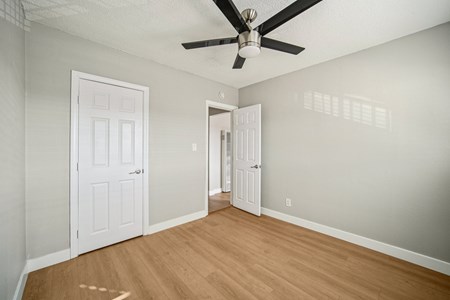 A room with a ceiling fan and two doors.